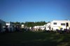 Motorhomes parked on grass with campers enjoying outdoor life.
